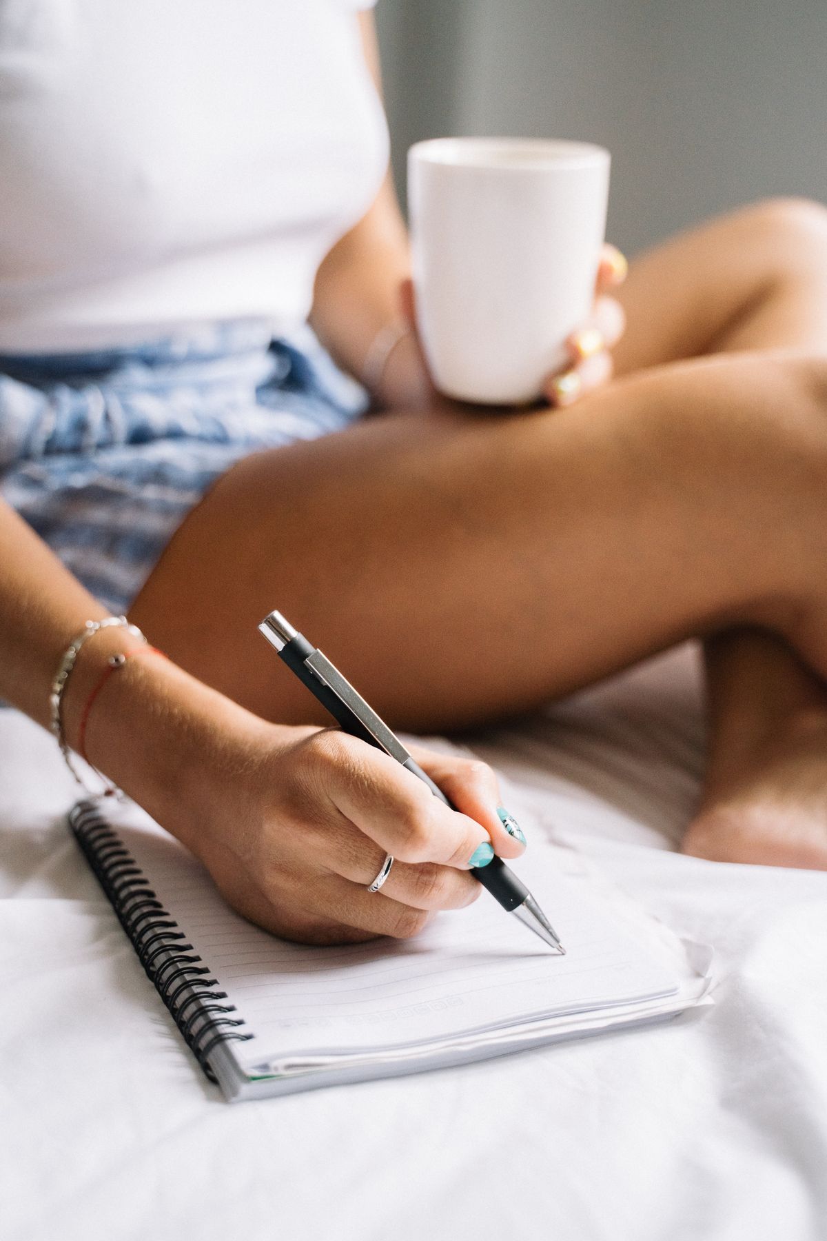 Pessoa anotando um hábito diário em um caderno, com uma xícara de café ao lado